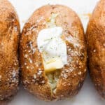 Three baked potatoes the middle with sour cream and butter.