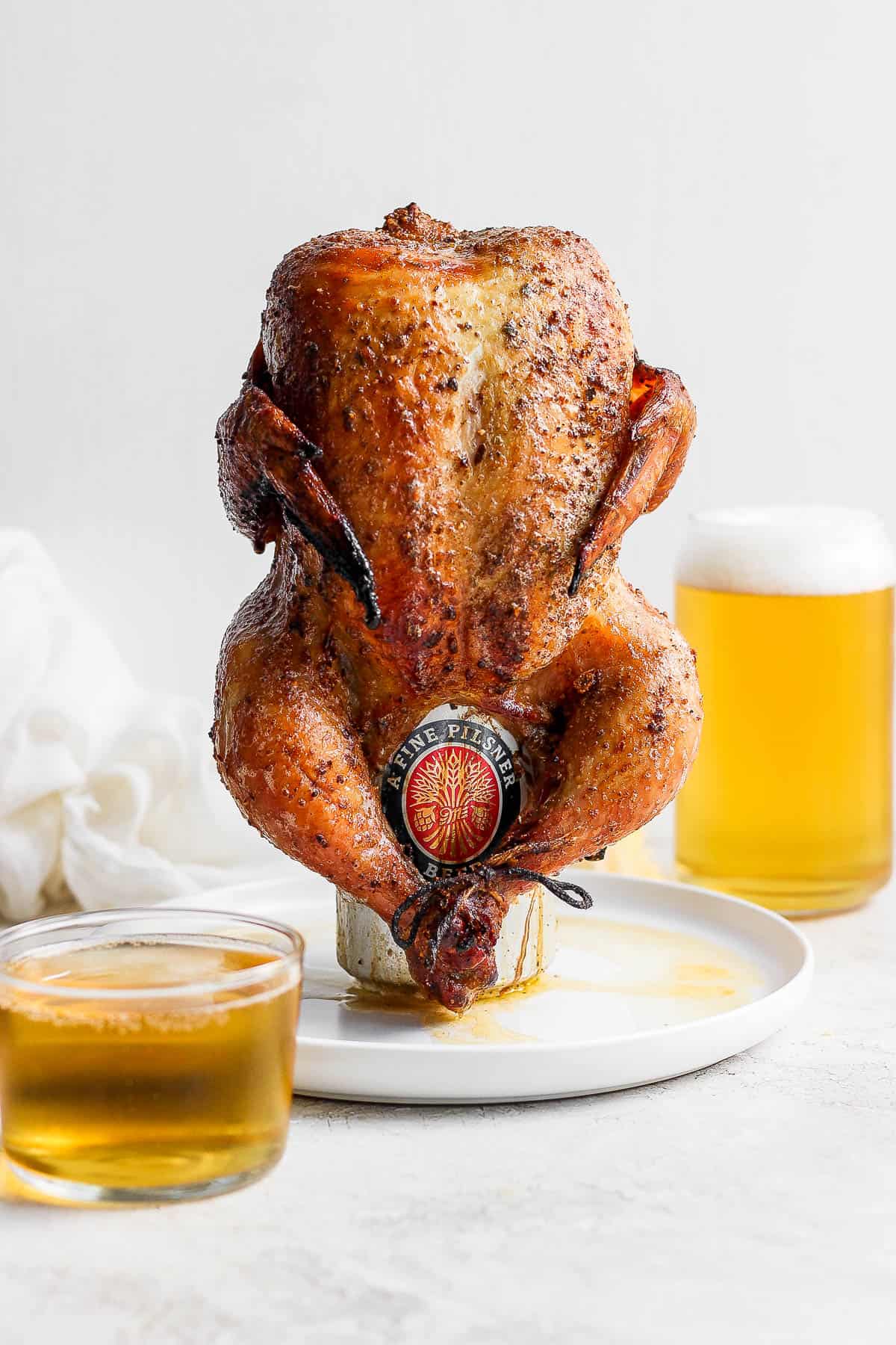 Smoked beer can chicken with can still on sitting on a plate. 