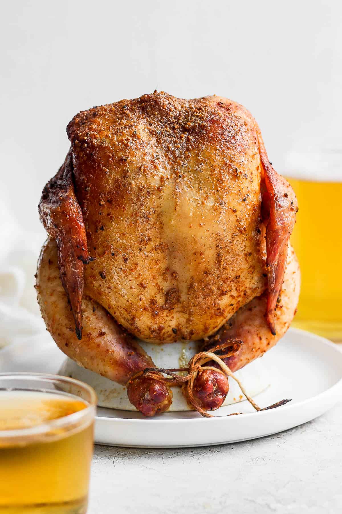 Smoked beer can chicken still on a chicken throne on a plate. 
