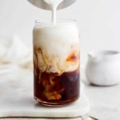 A glass of vanilla sweet cream cold brew with sweet cream being poured on top.