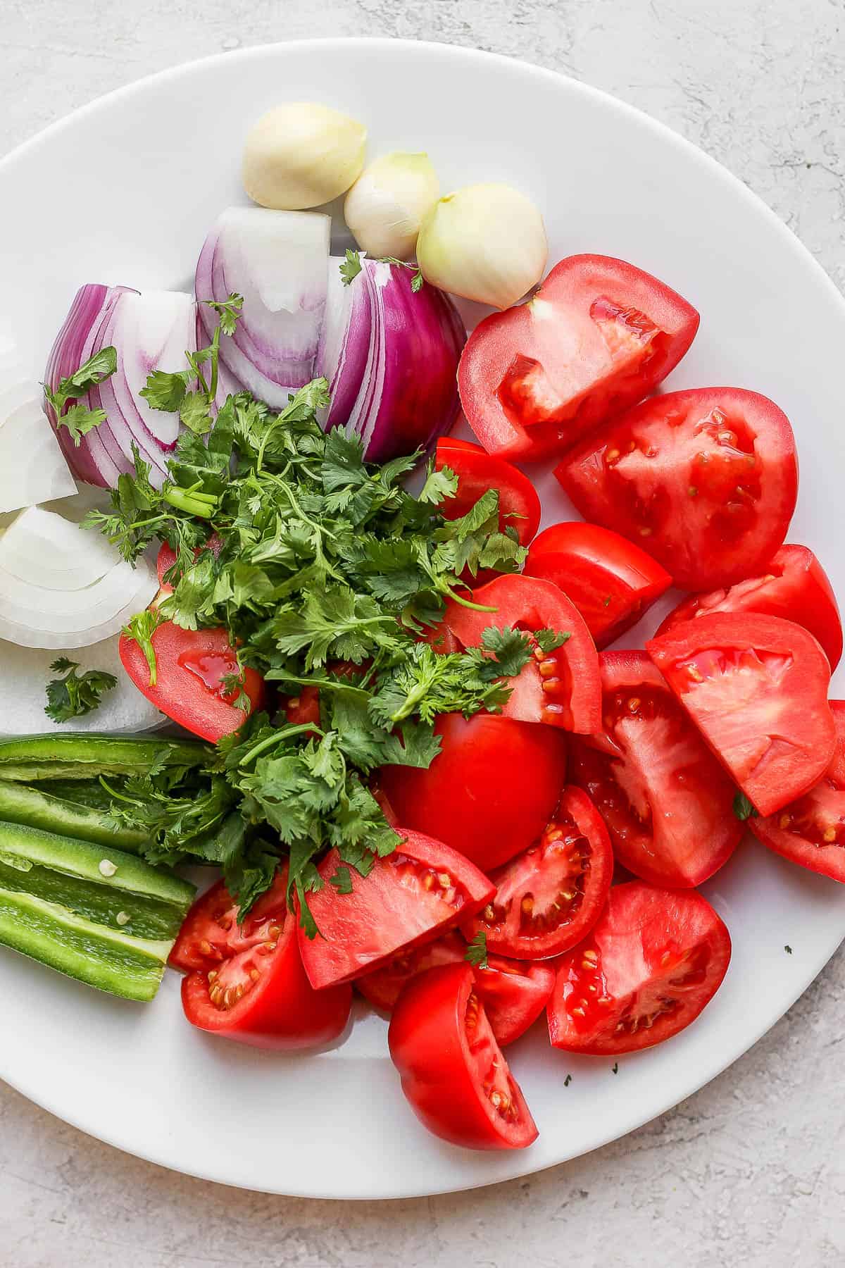 Plate full of blender salsa ingredients. 