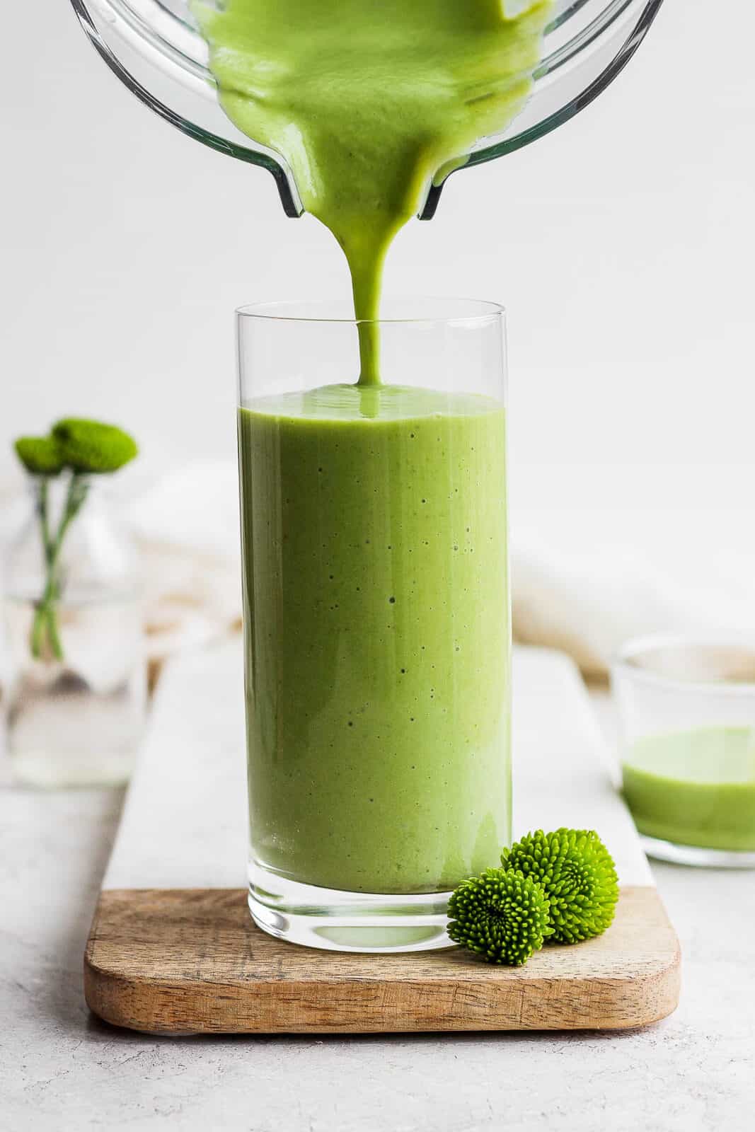 Pouring a green smoothie from the blender into a glass.