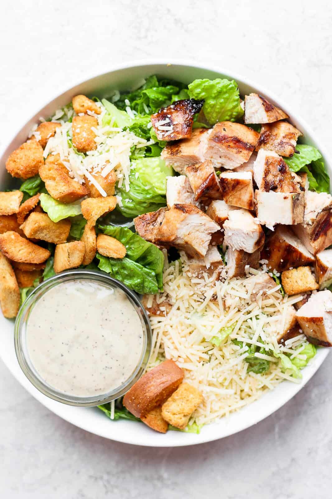 Grilled chicken caesar salad with a small dish of dressing.