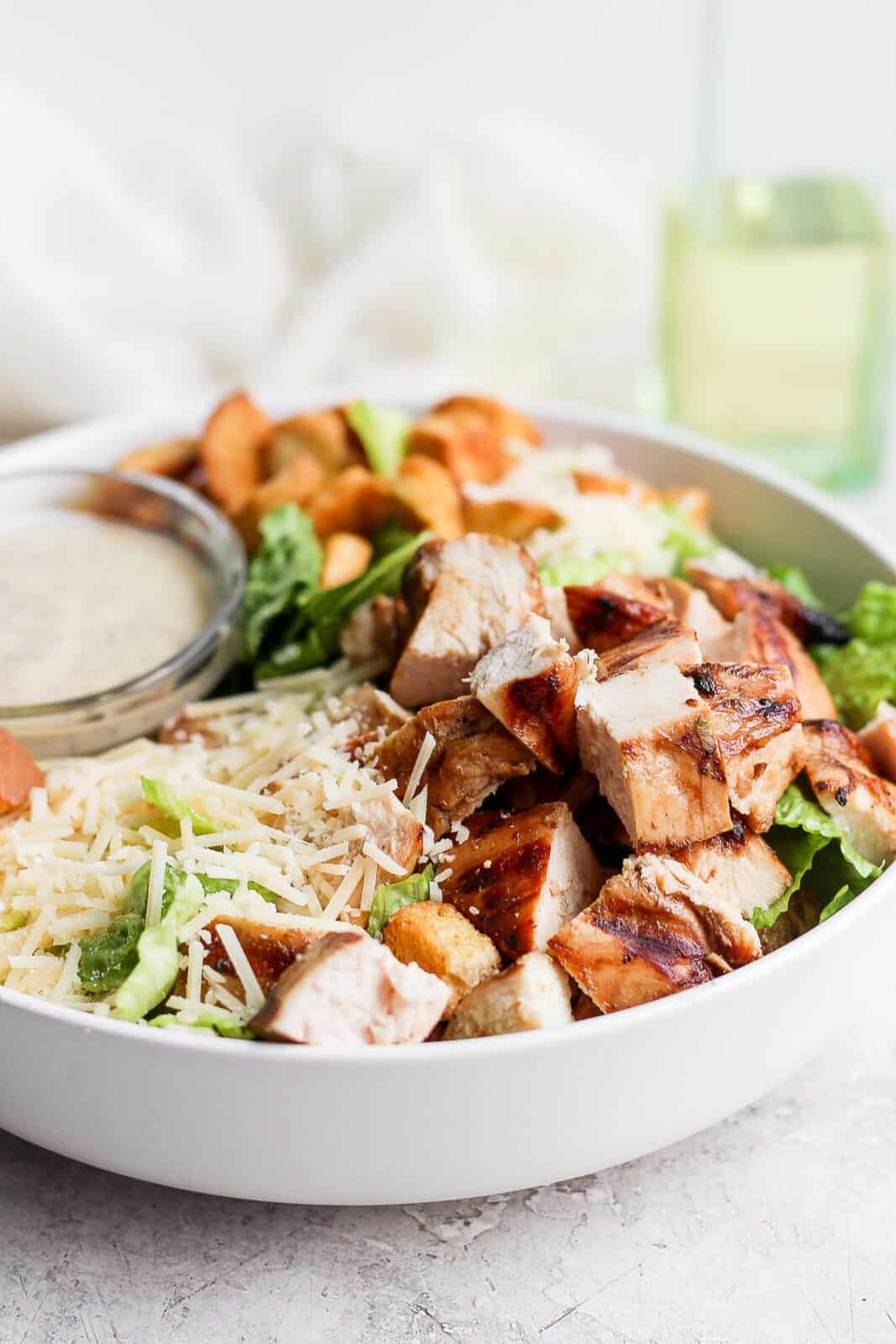 Grilled chicken caesar salad with a small dish of dressing.