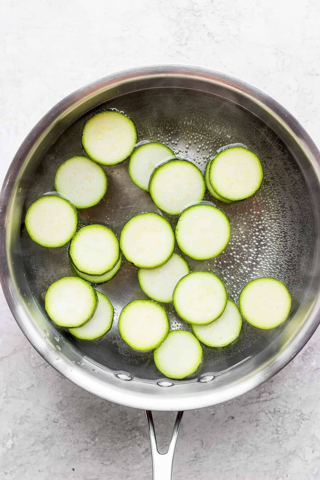 Zucchini slices in a pot water being blanched.