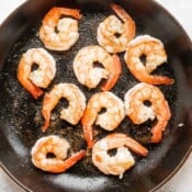 Large shrimp searing in a cast iron skillet.