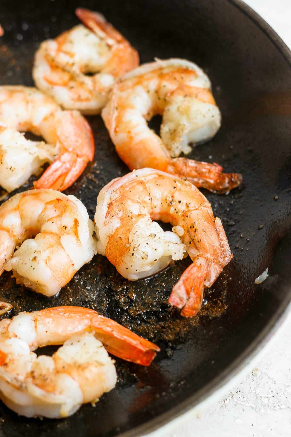 Shrimp being cooked in a cast iron skillet.