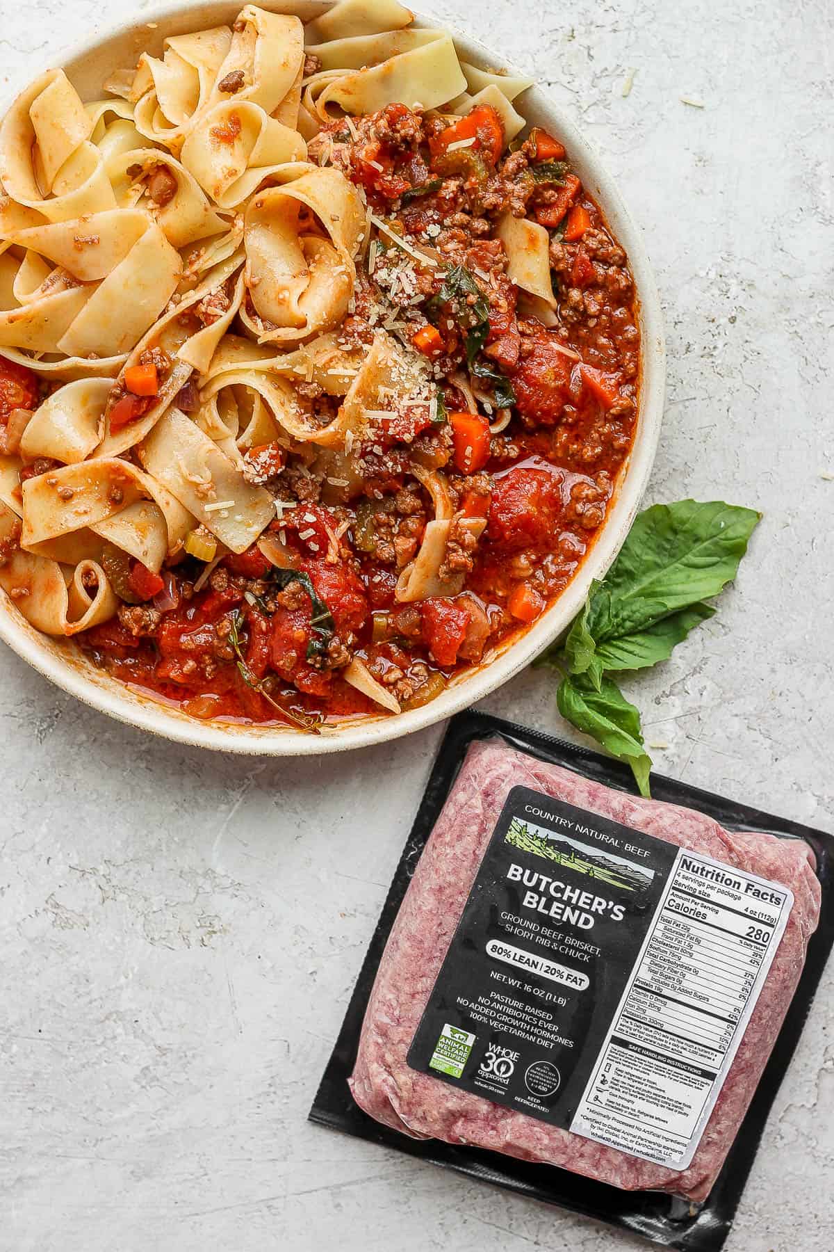 Bowl of pappardelle bolognese with a package of butcher's blend ground beef.