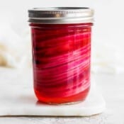 A jar of quick pickled red onions with the top on.