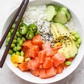 Top down shot of a salmon poke bowl with avocado, mango, cucumber and edamame.