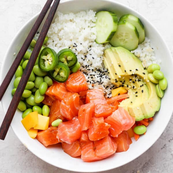 Top down shot of a salmon poke bowl with avocado, mango, cucumber and edamame.