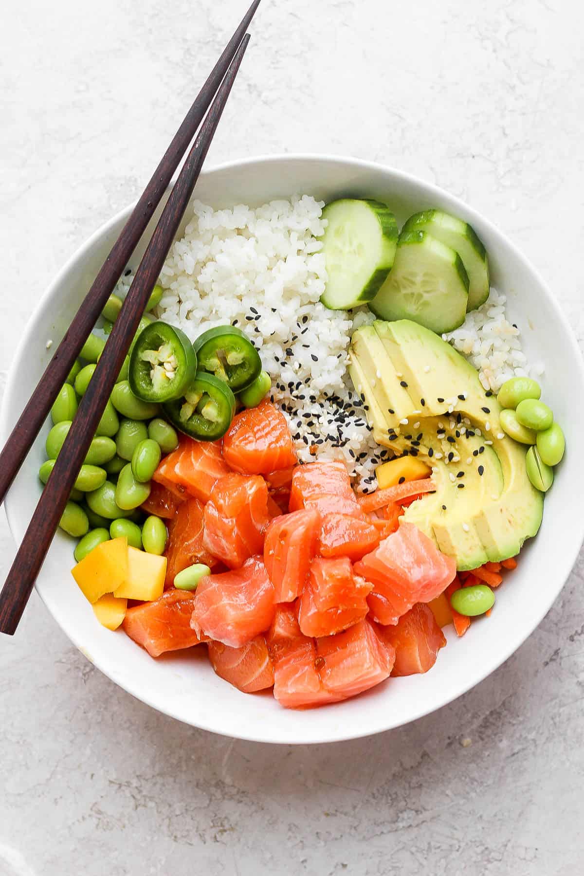 A salmon poke bowl with chopsticks.