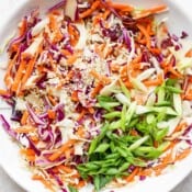 Sesame ginger slaw in a white bowl with some green onions.