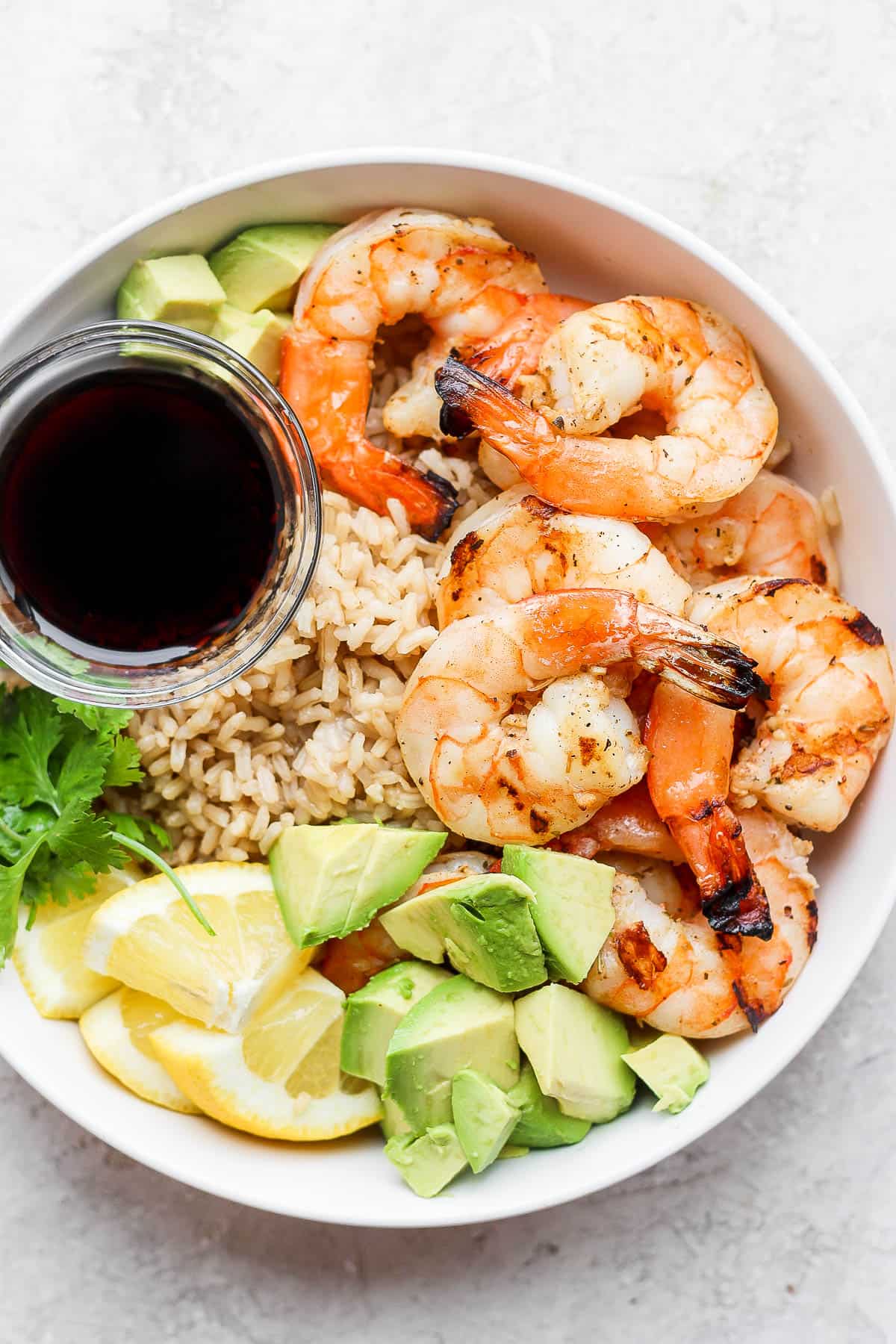 Shrimp rice bowl with a dish of soy sauce.