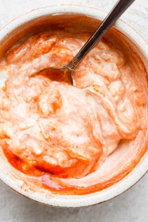 A bowl of spicy mayo with a spoon sticking out.