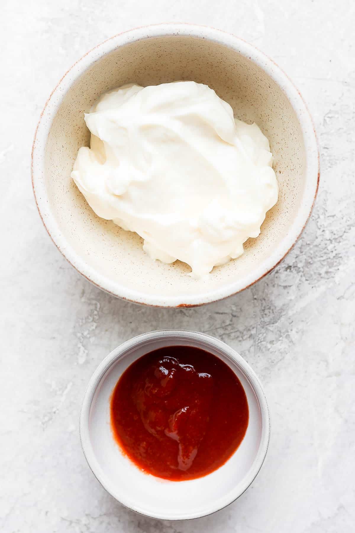 Two bowls; one with mayo and one with siracha in it.