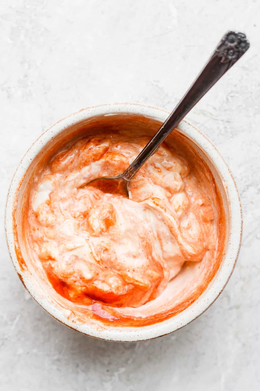 A small bowl of sriracha mayo with a spoon.