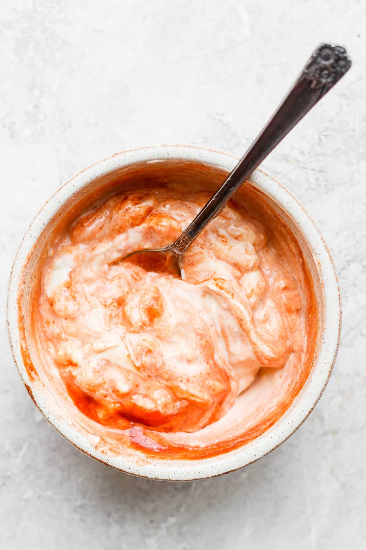 A bowl of spicy mayo with spoon sticking out.