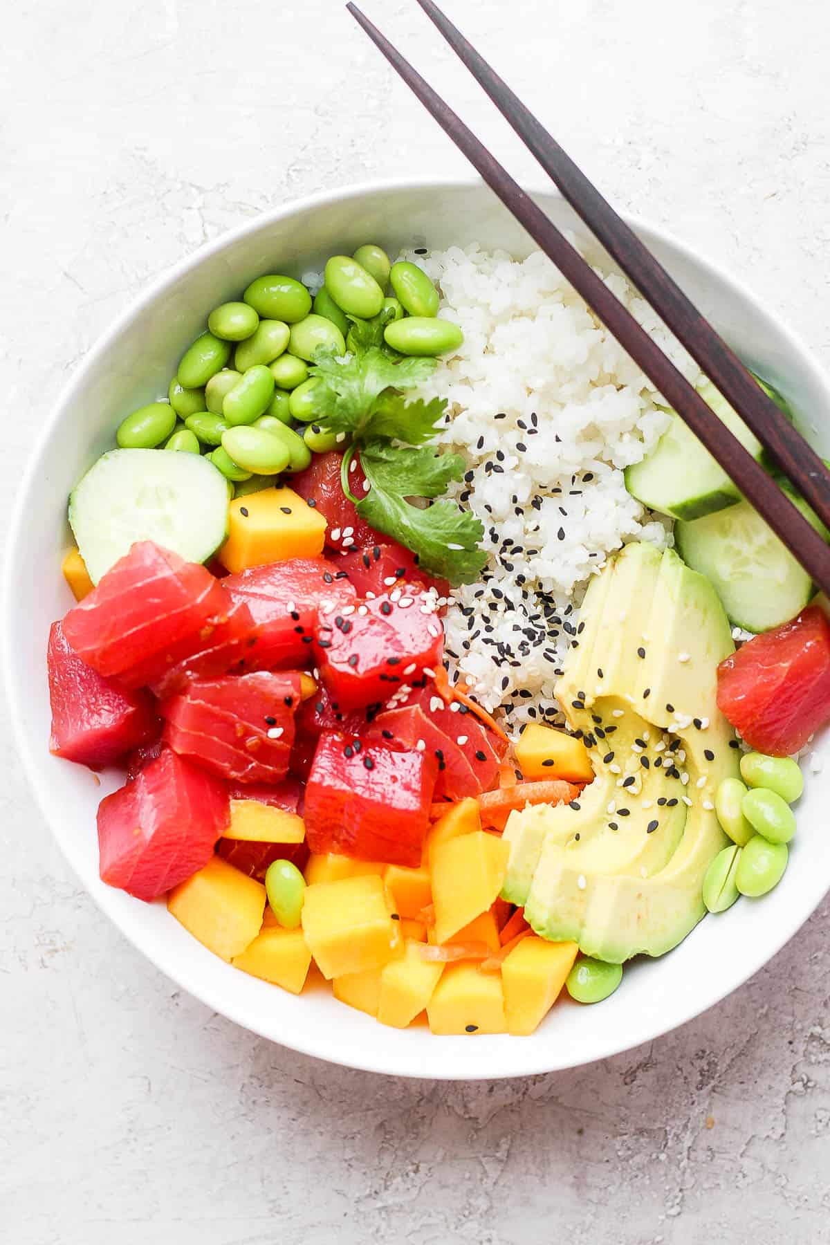 Tuna poke bowl with sushi rice, edamame, cucumber, mango, avocado and cilantro. 