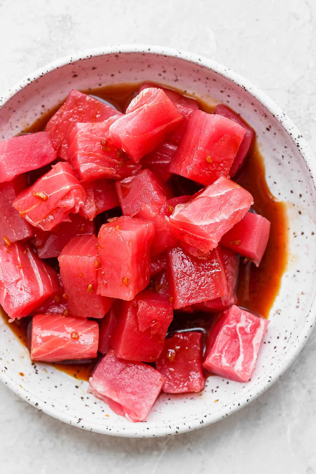 Chunks of cut up raw ahi tuna in a marinating in poke sauce. 