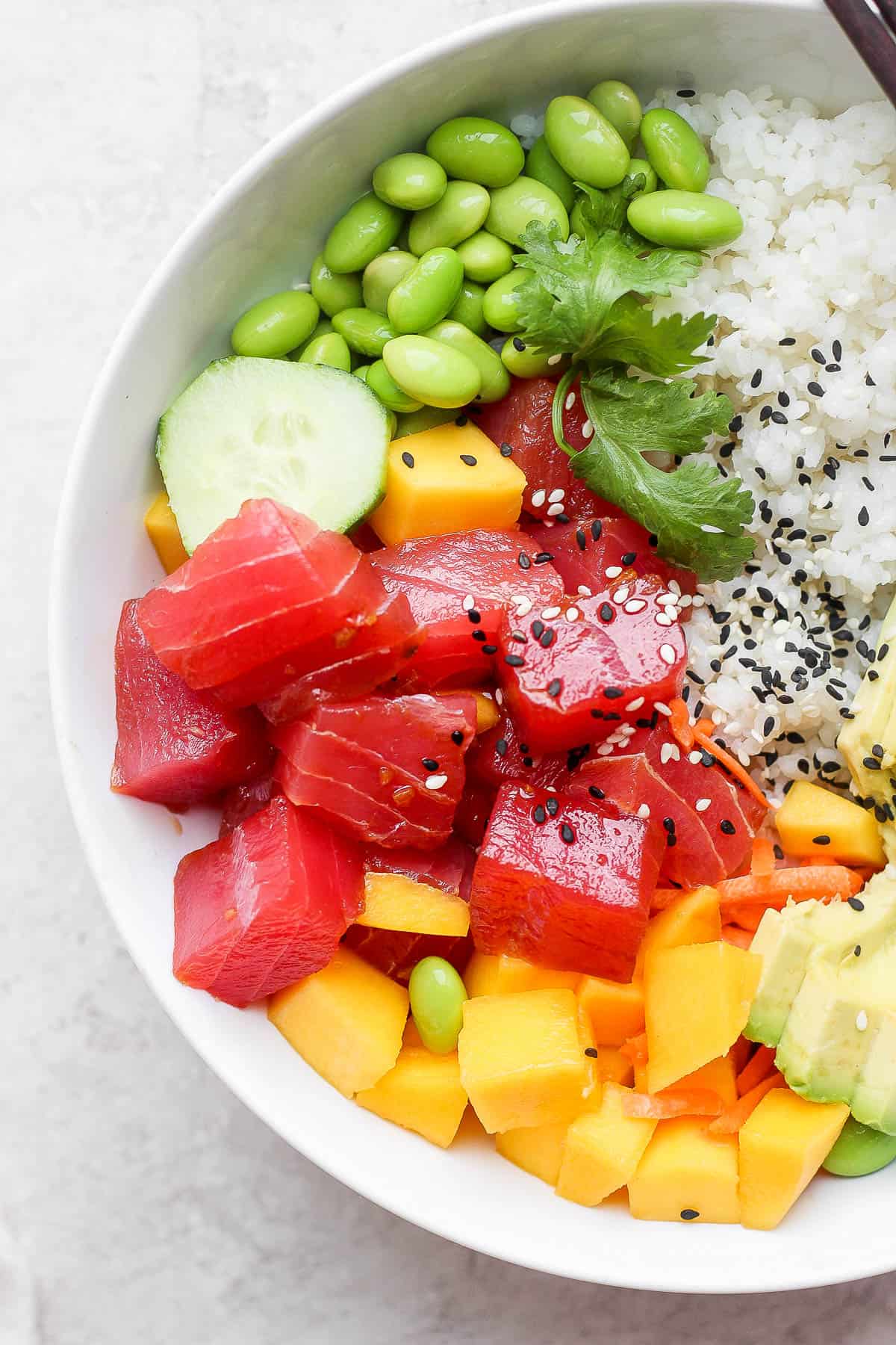 Tuna poke bowl with sushi rice, edamame, cucumber, mango, avocado and cilantro. 