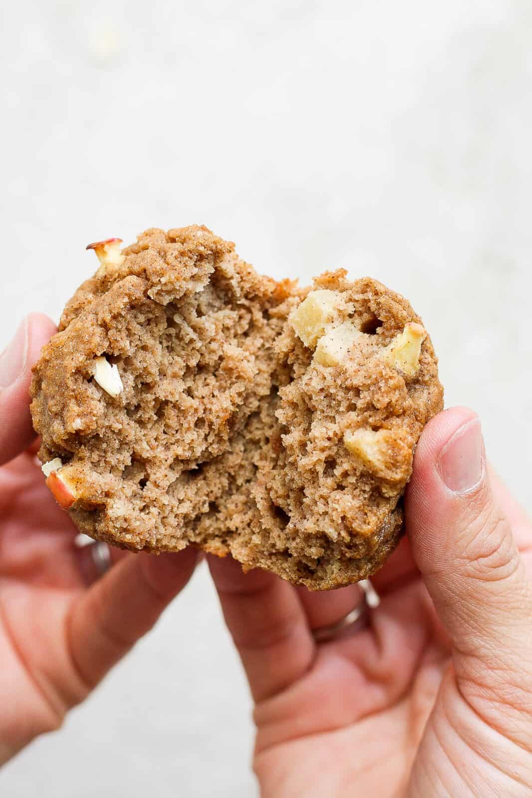 An apple cinnamon muffins being broken in half.