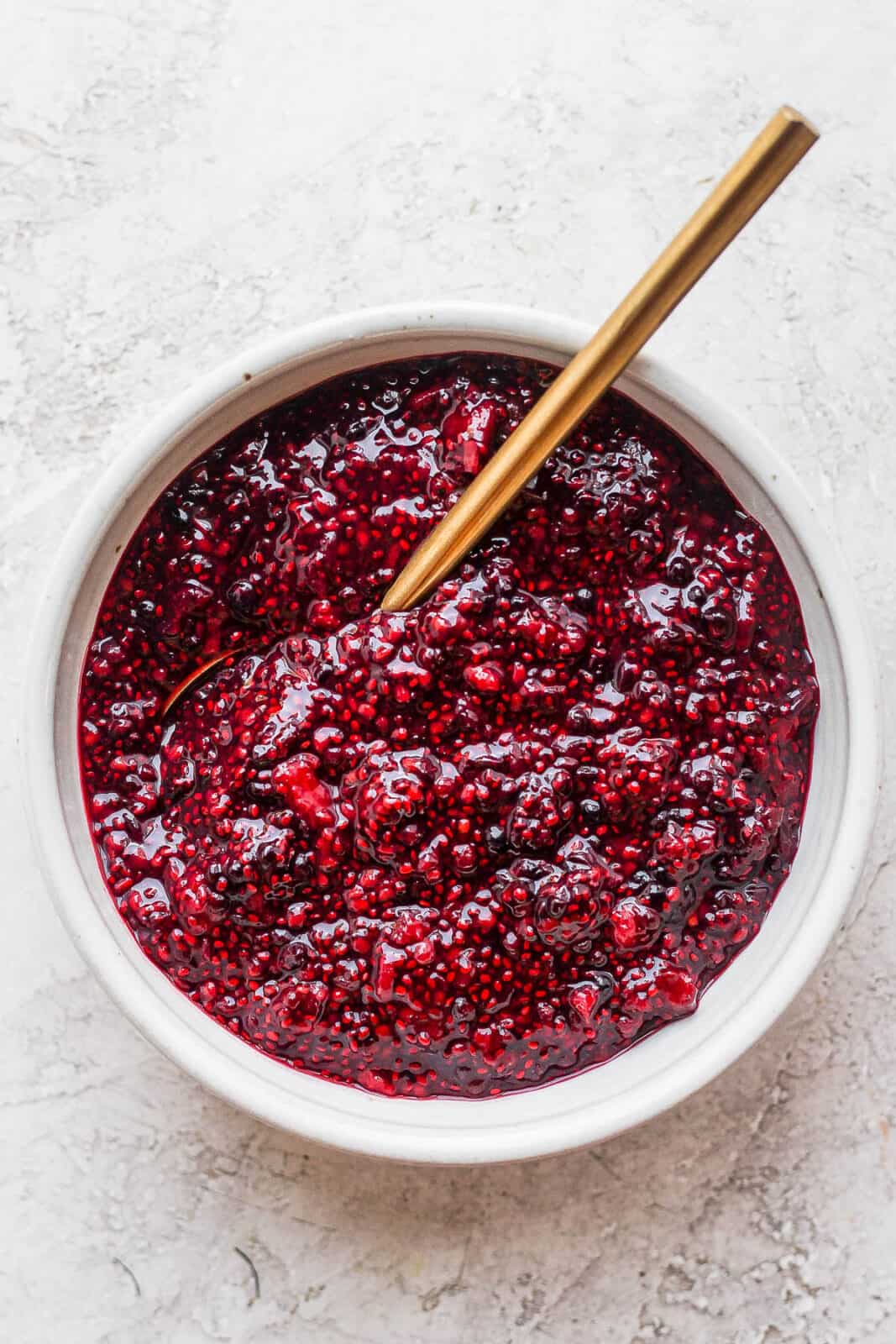 Bowl of chia seed jam with golden spoon sticking out. 