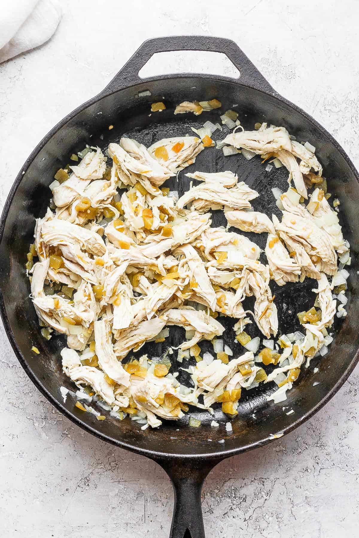 Chicken mixture for green chicken enchiladas in a cast iron skillet.