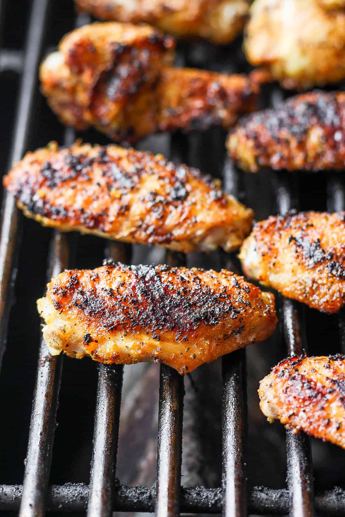 Seasoned chicken wings on the grill grates.