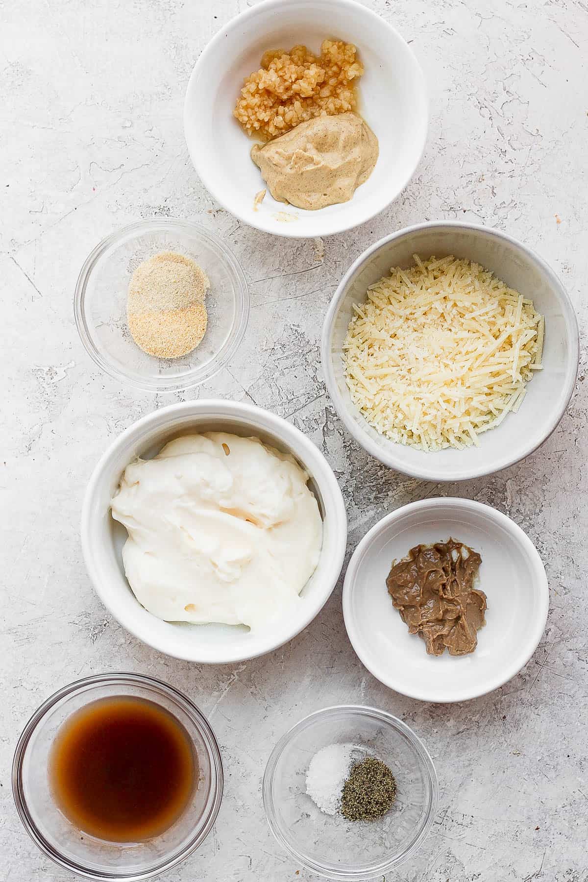 Healthy caesar dressing ingredients in small bowls.