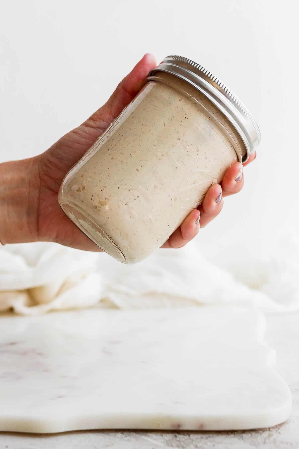 Healthy caesar dressing being shaken in a mason jar.