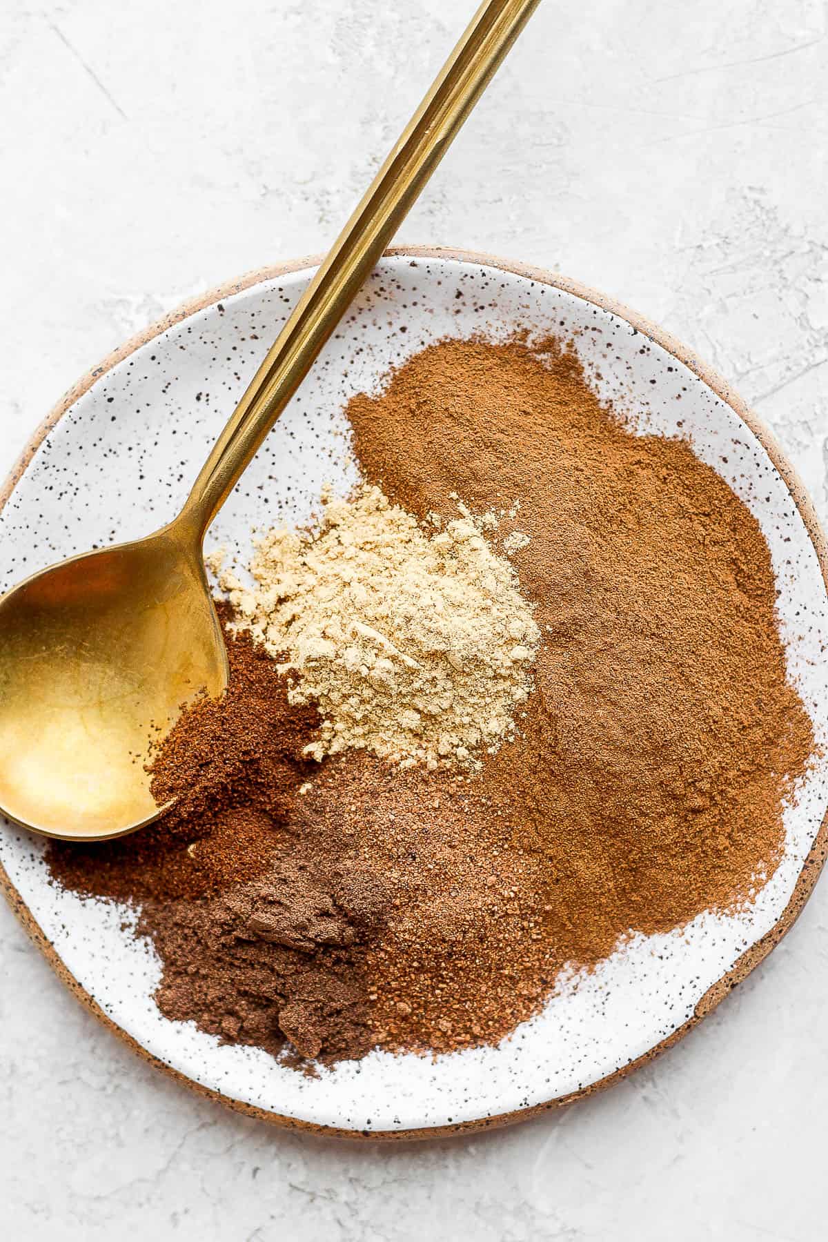 Pumpkin spice ingredients on a plate with a spoon.