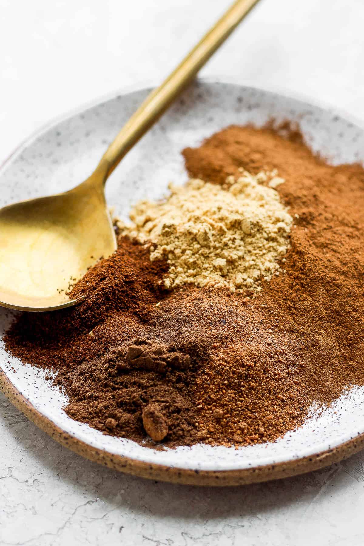 Pumpkin spice ingredients on a plate with a spoon.