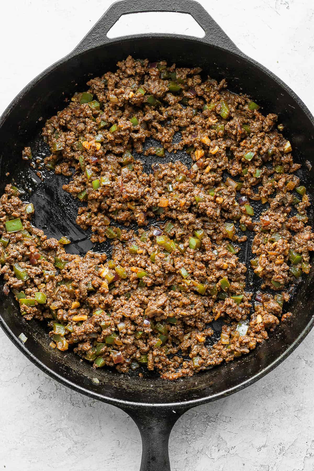 A cast iron skillet filled with sloppy Joe filling. 