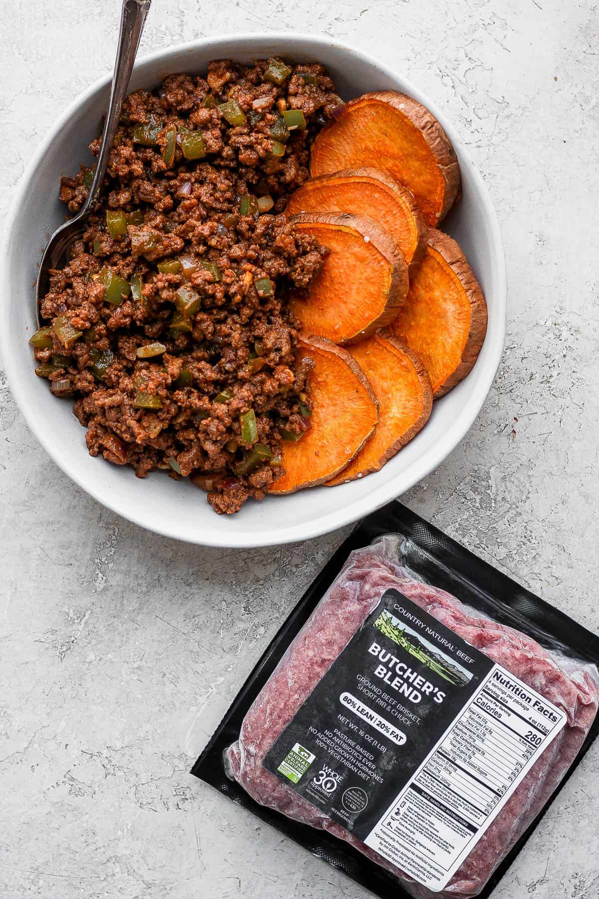 A bowl of sloppy Joe mix with roasted sweet potatoes and a package of Country Natural Beef ground beef. 
