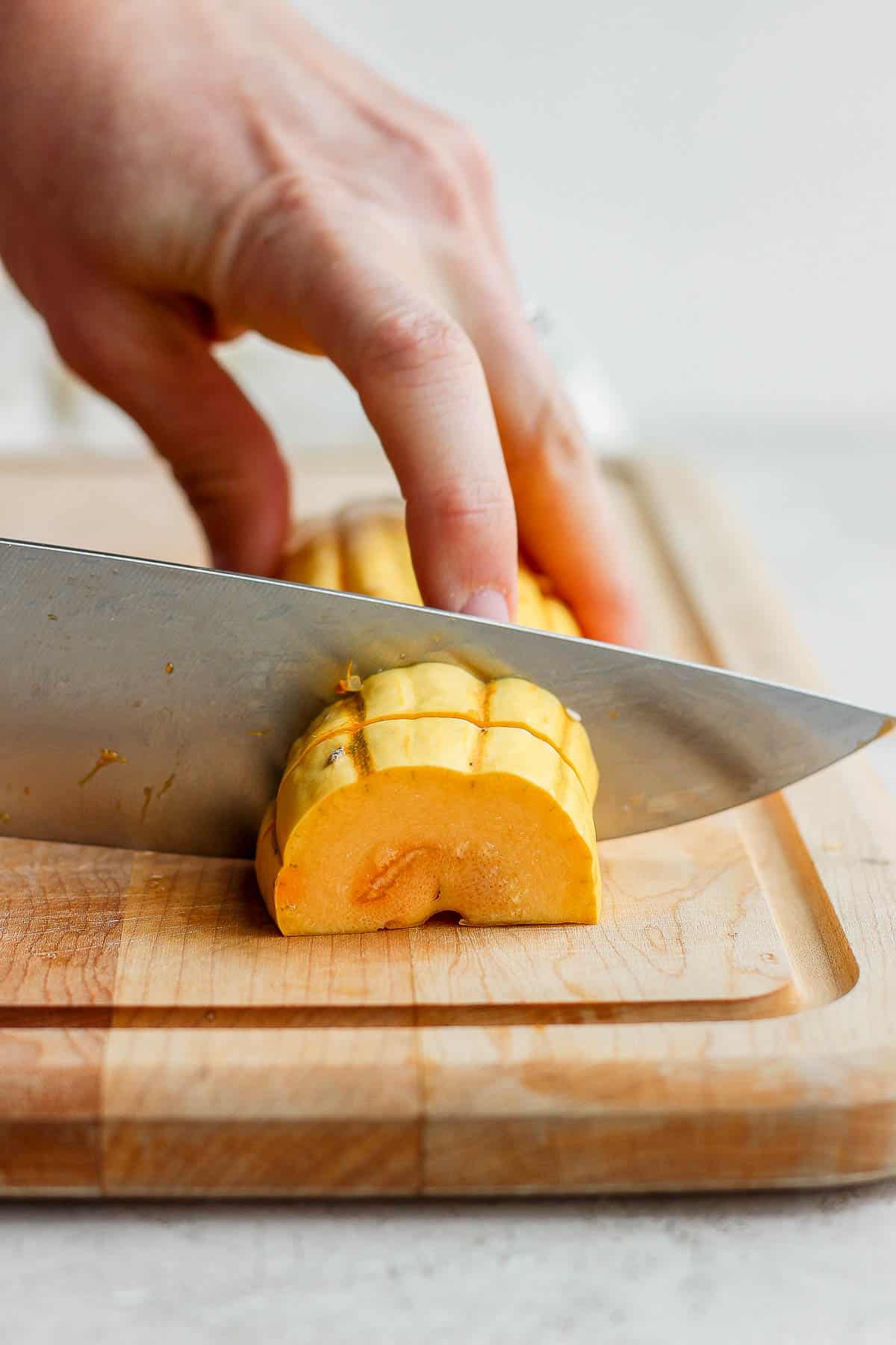 A delicata squash being cut into slices.