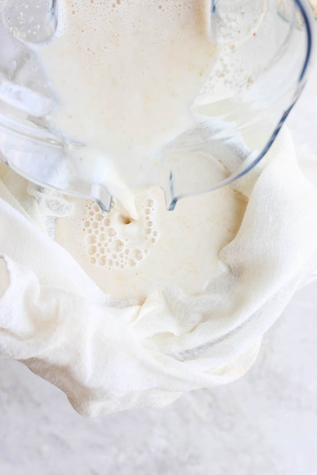 Oat milk being poured into a cheesecloth.