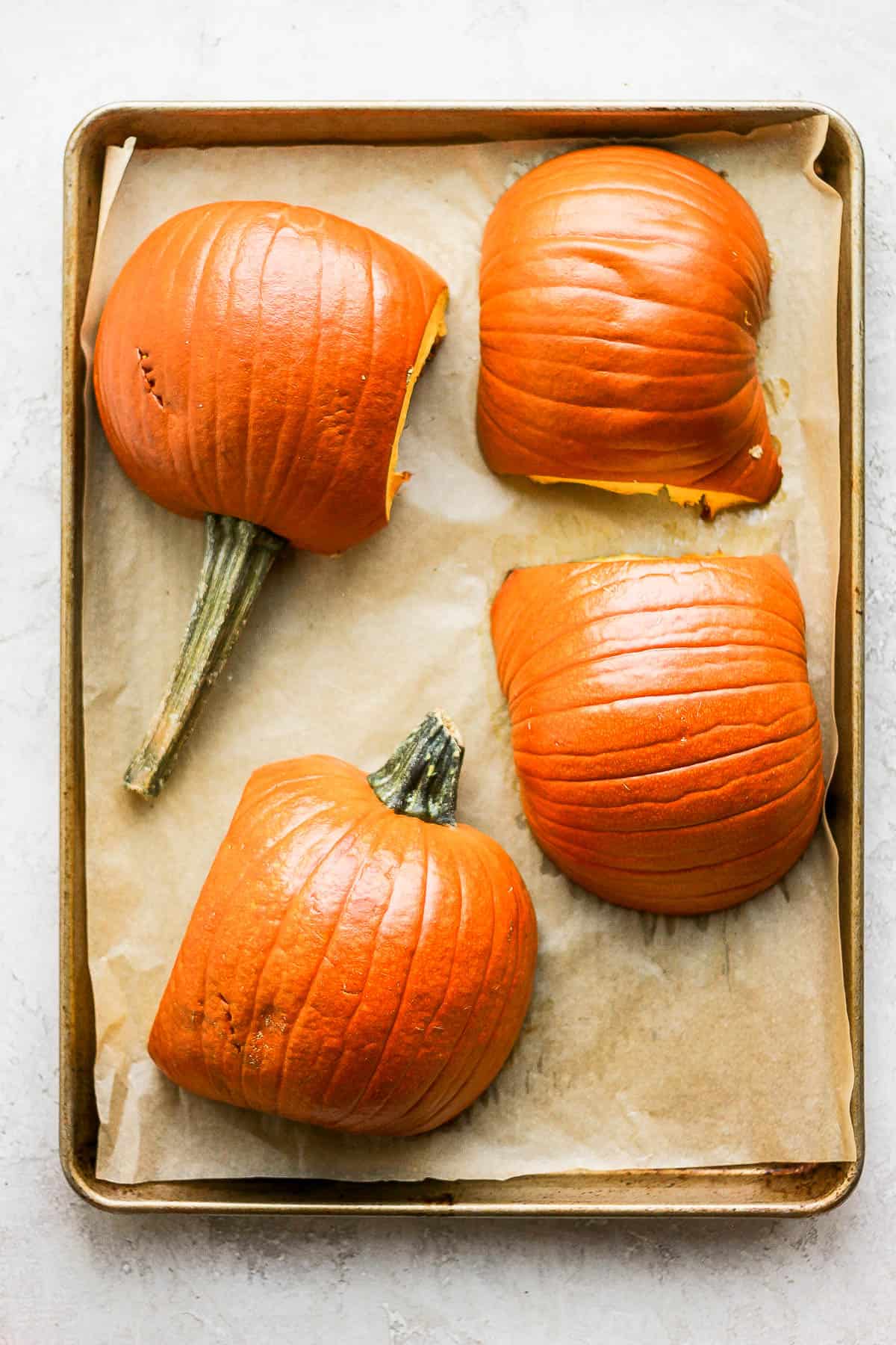 Pumpkin halves on a baking sheet after baking.