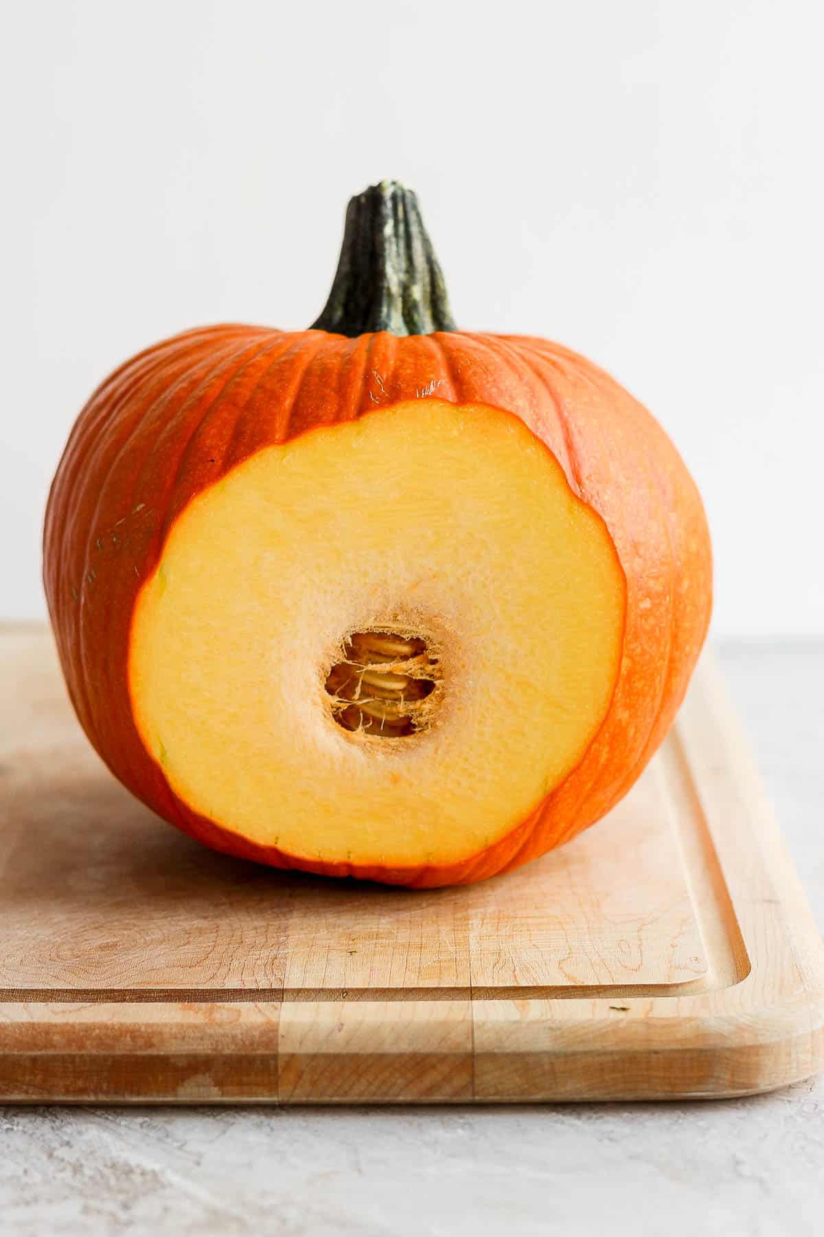 A pumpkin with a thin slice cut off the side.