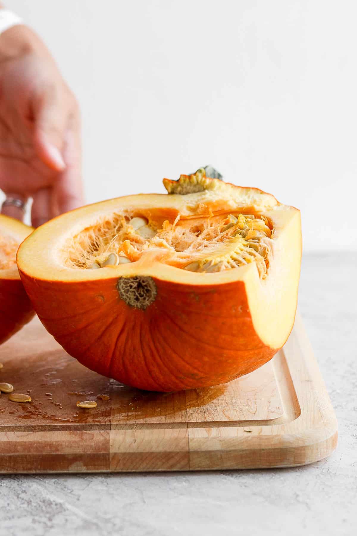 Half of a small, baking pumpkin on a cutting board.