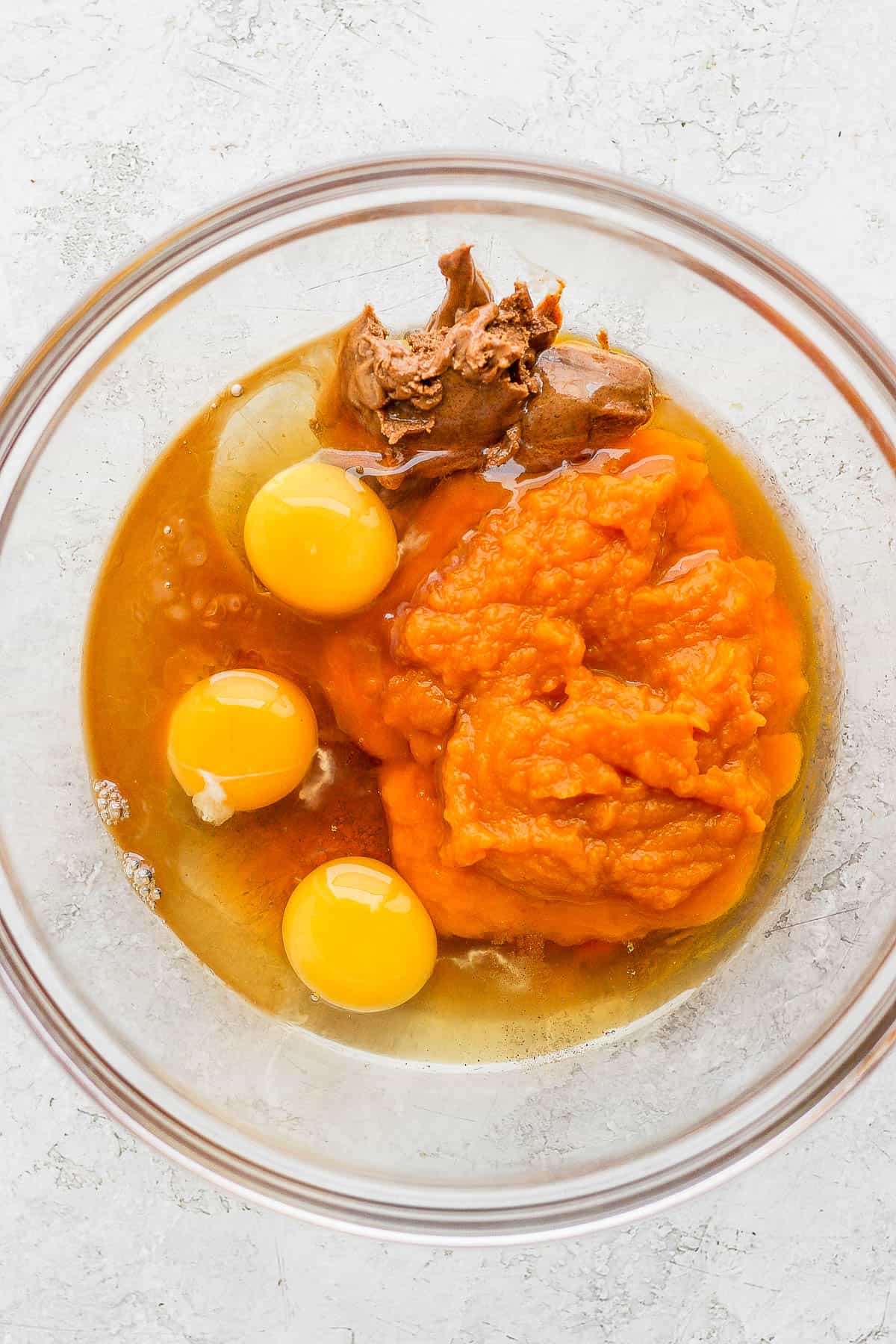 Wet ingredients for pumpkin bread in a mixing bowl.