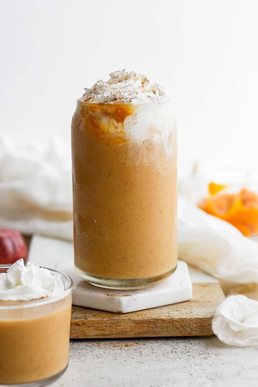 Pumpkin smoothie in a glass with whipped cream on top.