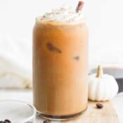 A tall glass of pumpkin cold brew with whipped cream on top.