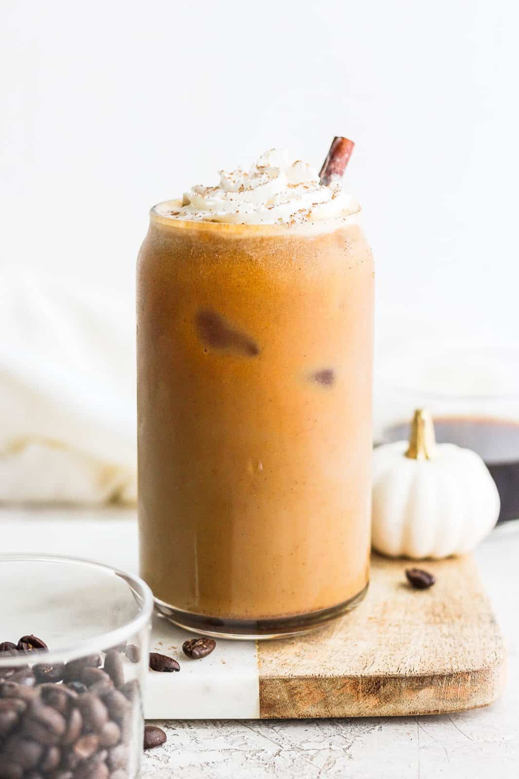 Glass of pumpkin cold brew with whipped almond milk and sprinkled with pumpkin spice.