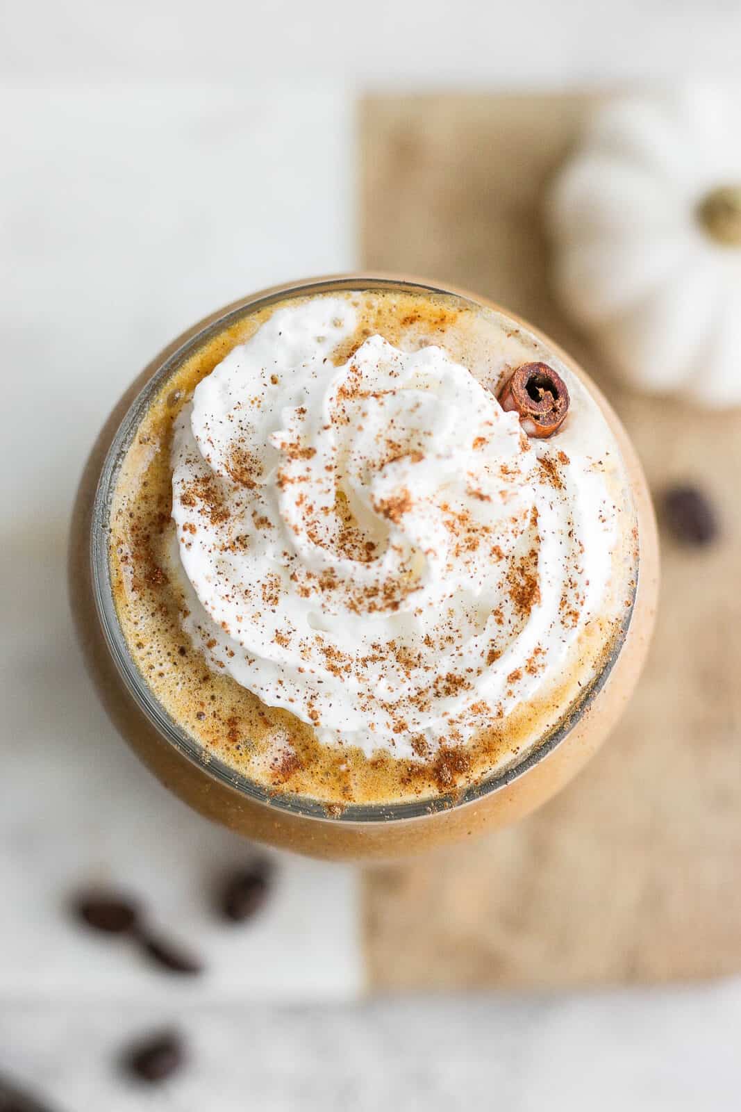 Top shot of a glass of pumpkin cold brew with whipped almond milk and sprinkled with pumpkin spice.