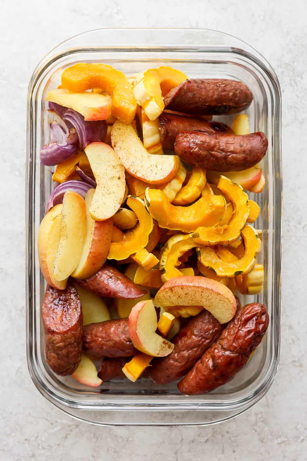 The sausage sheet pan meal in a container to go in the fridge.