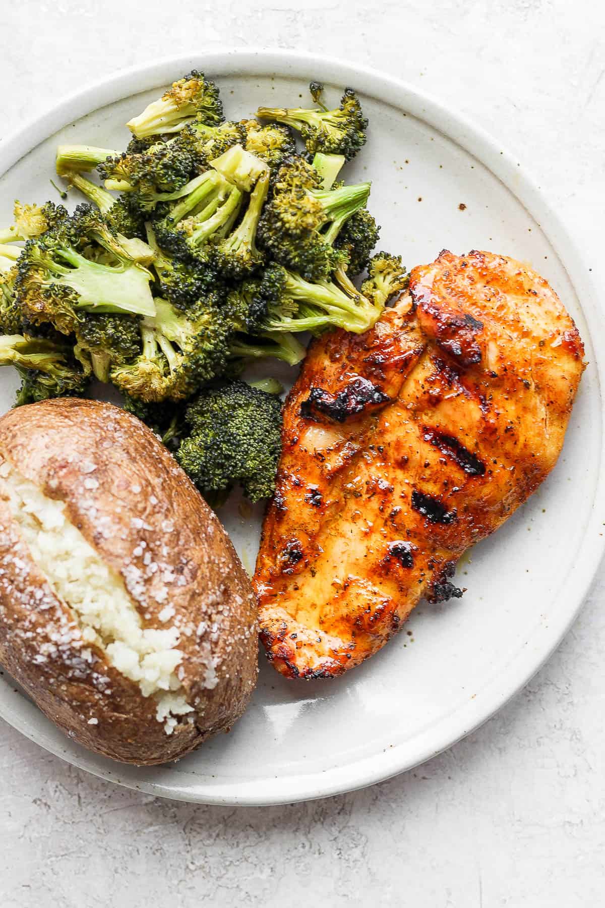 Plate of smoked chicken, smoked chicken broccoli and a smoked potato. 