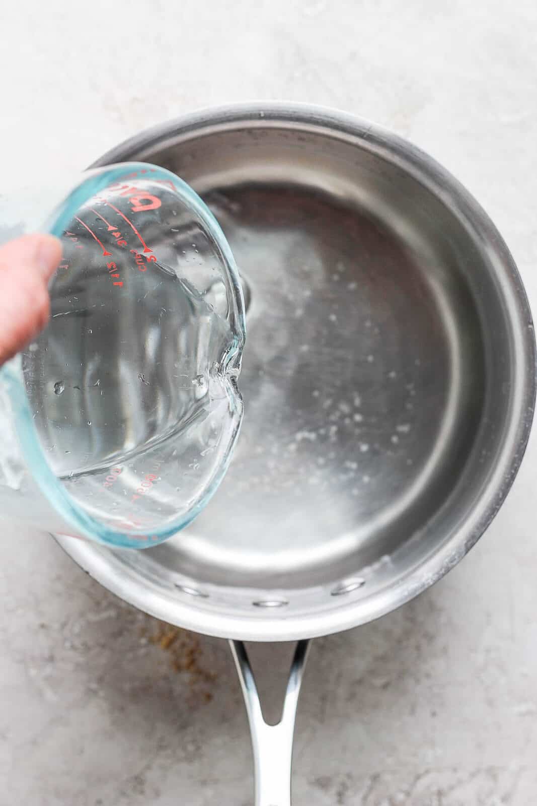 Someone pouring water into a saucepan.