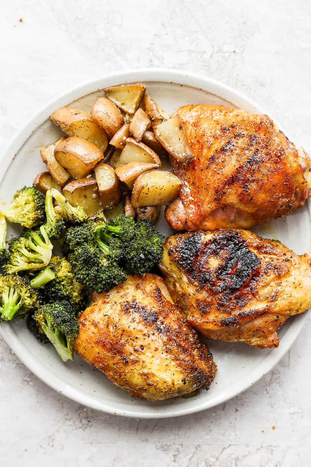 A plate of smoked chicken thighs, smoked broccoli and smoked potatoes. 