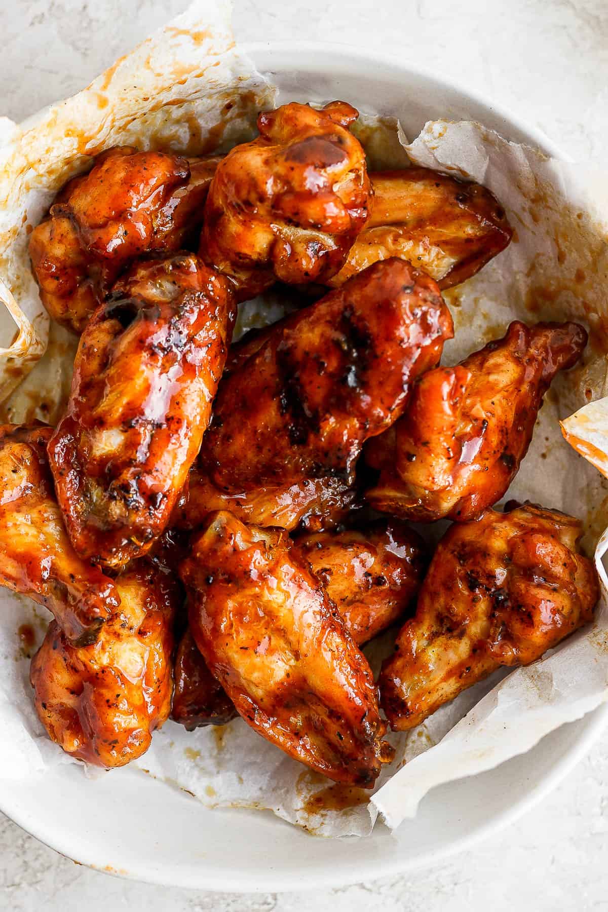Bowl of chicken wings with bbq sauce on them. 